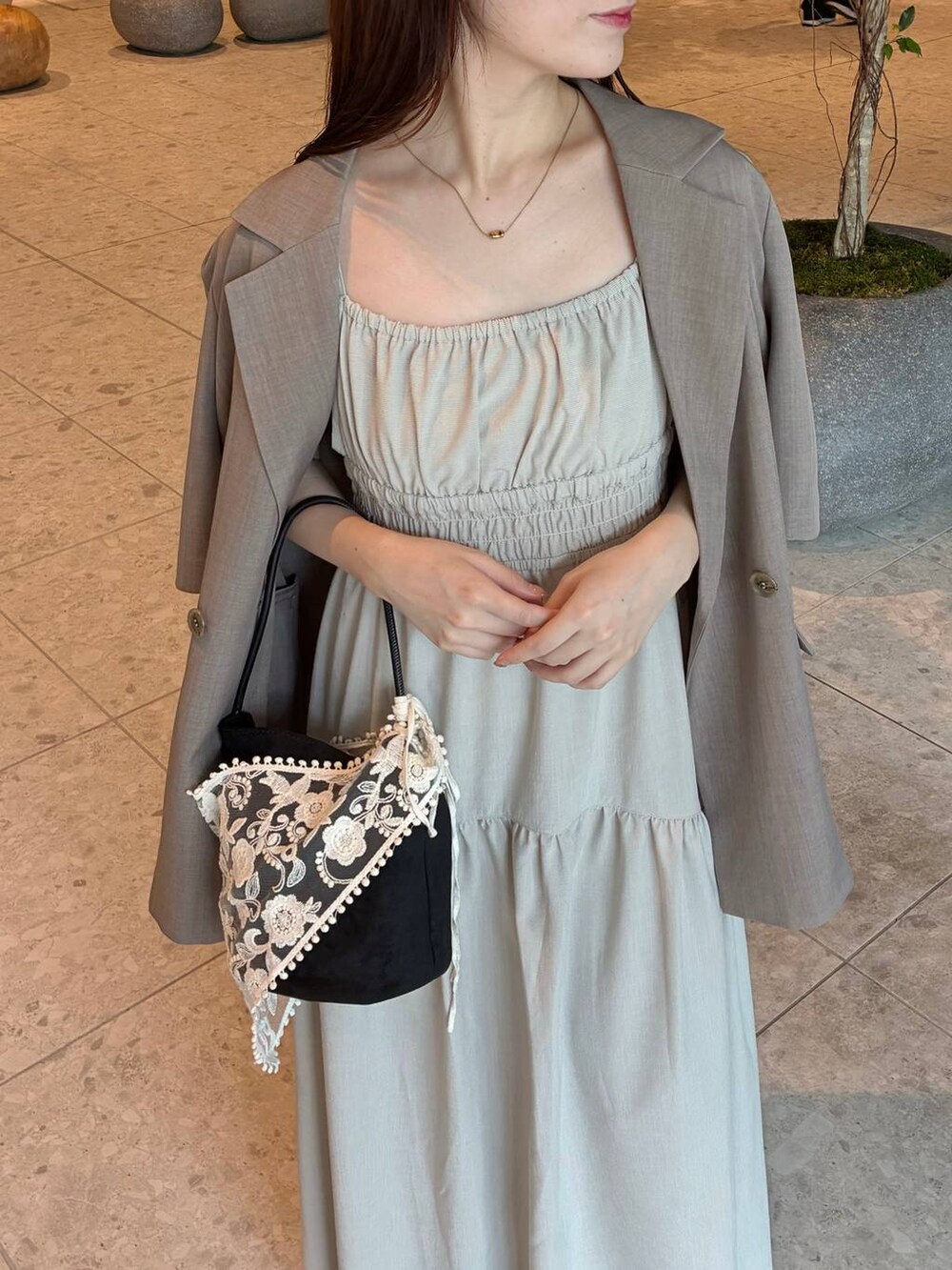 ベージュ系のテーラードジャケット、ベージュ系のワンピース、ブラック系のスリッポンを着用したレディースの夏コーディネートの3枚目の写真