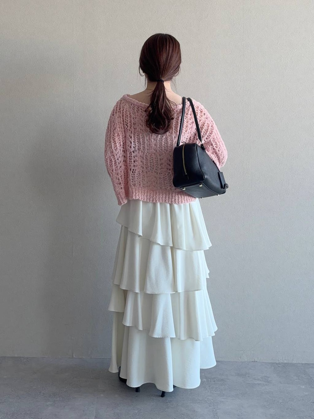 ブラック系のハンドバッグ、ブルー系のニット/セーター、ホワイト系のスカートを着用したレディースの冬コーディネートの2枚目の写真