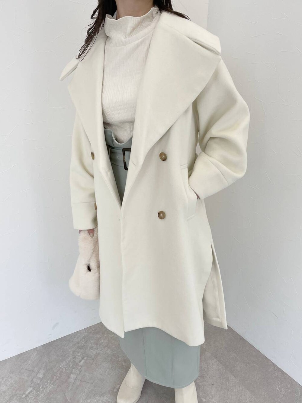 ホワイト系のブーツ、ホワイト系のハンドバッグ、ホワイト系のチェスターコートを着用したレディースの冬コーディネートの3枚目の写真