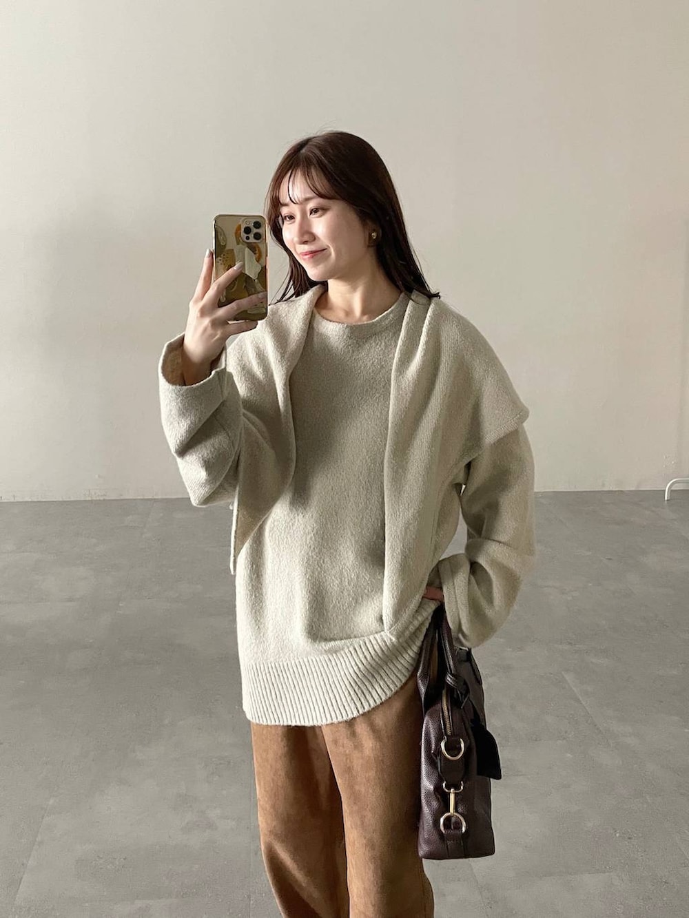 ブラウン系のボストンバッグ、ホワイト系のチェスターコート、ブラウン系のブーツを着用したレディースの秋コーディネートの3枚目の写真