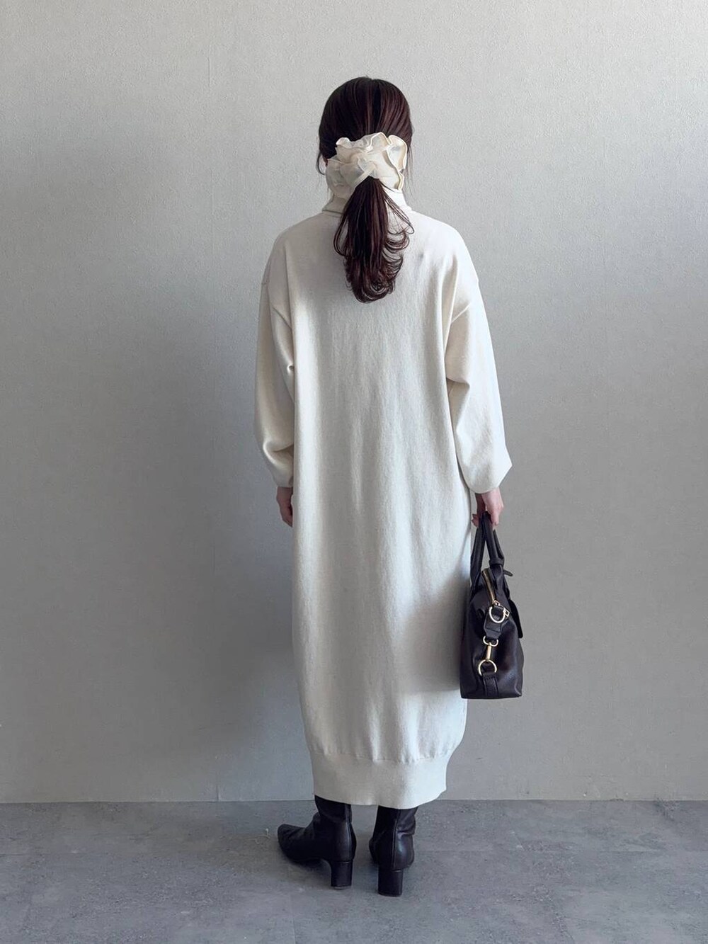 ブラウン系のボストンバッグ、パープル系のチェスターコート、ブラウン系のブーツを着用したレディースの冬コーディネートの4枚目の写真