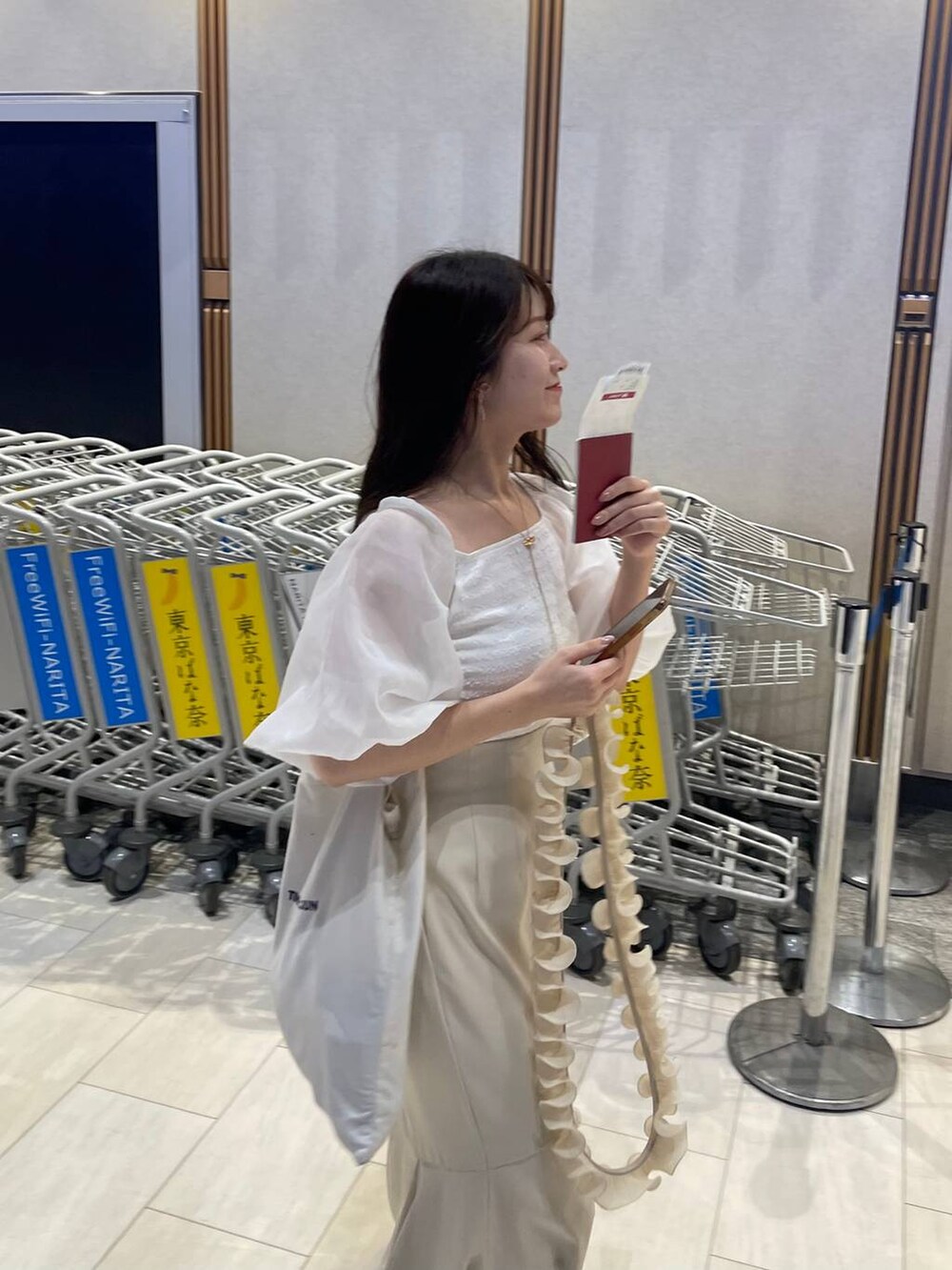 ホワイト系のTシャツ/カットソー、ホワイト系のサンダル、ホワイト系のスマホグッズを着用したレディースの夏コーディネートの2枚目の写真