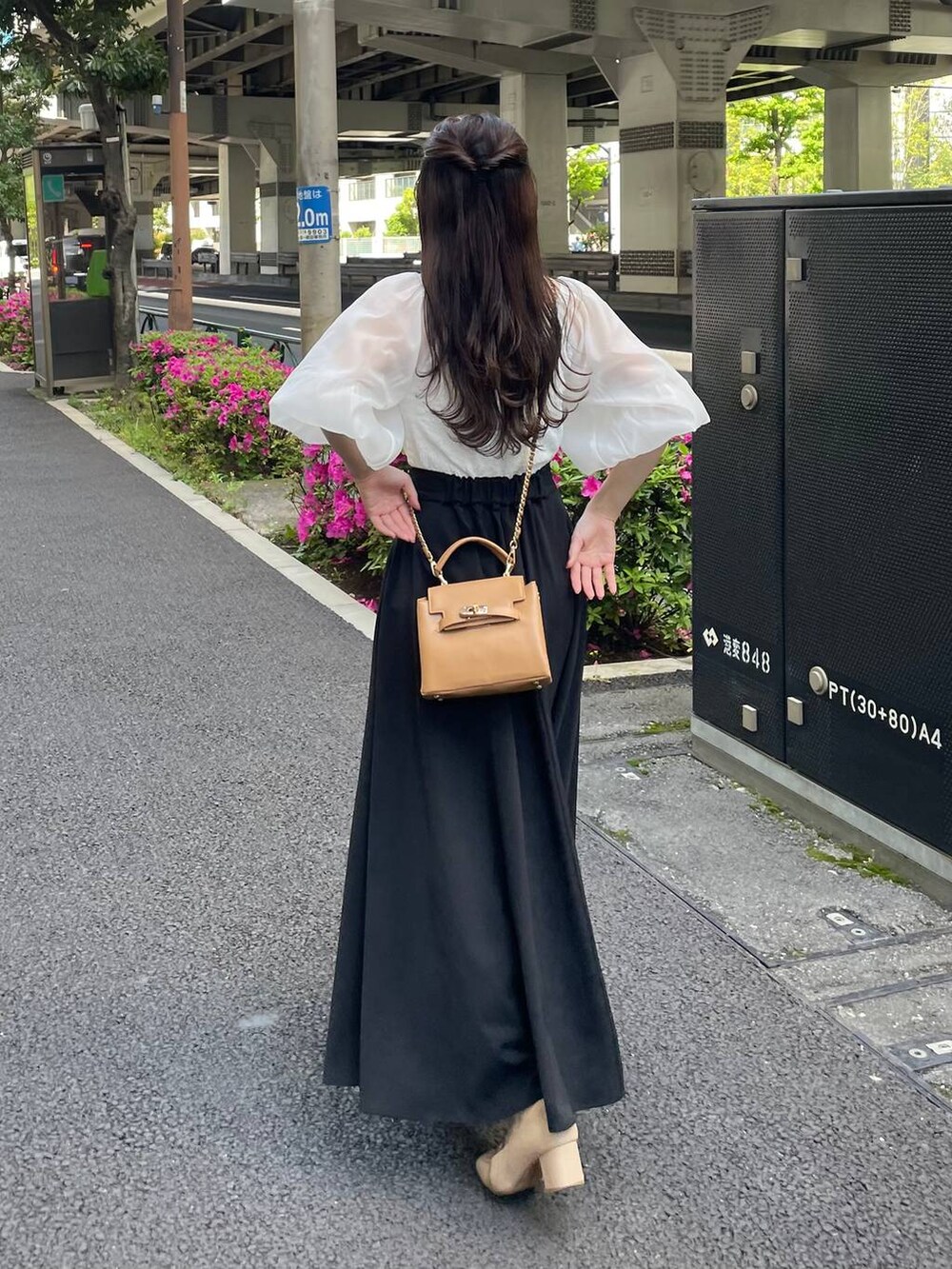 ホワイト系のTシャツ/カットソー、ブラック系のスカート、ブラウン系のショルダーバッグを着用したレディースの春コーディネートの2枚目の写真