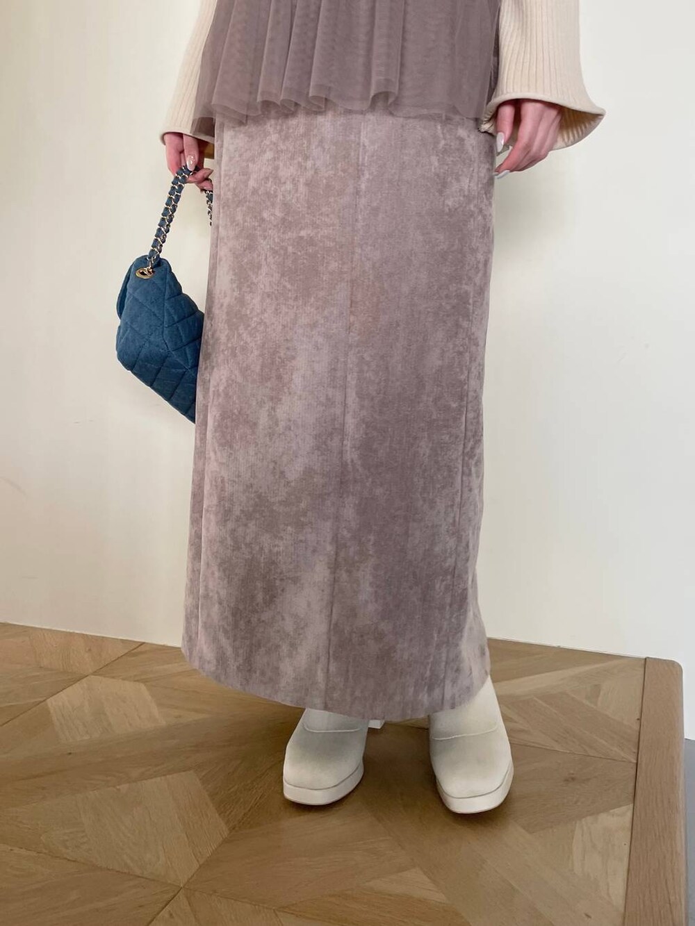 ブラウン系のスカート、ブルー系のショルダーバッグ、ホワイト系のブーツを着用したレディースの冬コーディネートの4枚目の写真