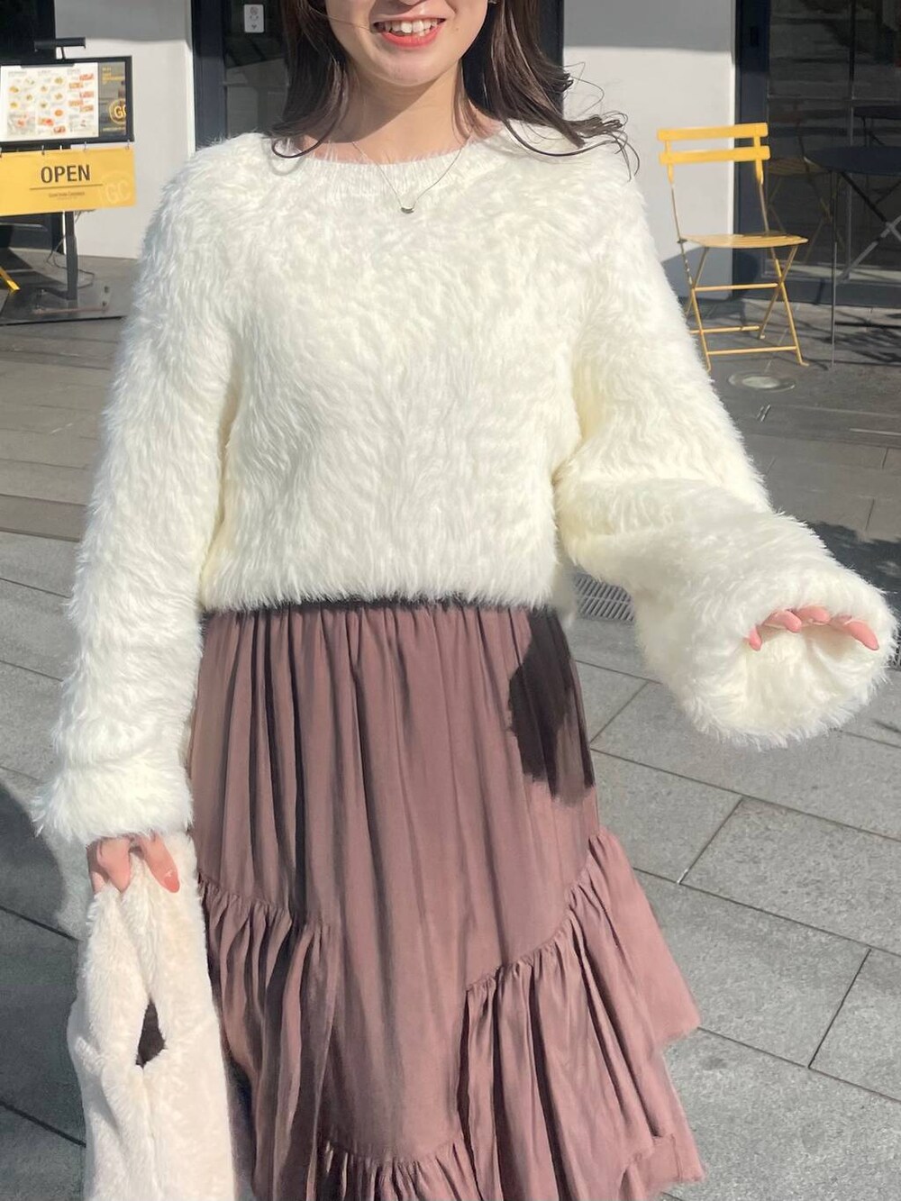 ブラウン系のスカート、ホワイト系のハンドバッグ、ホワイト系のニット/セーターを着用したレディースの冬コーディネートの2枚目の写真