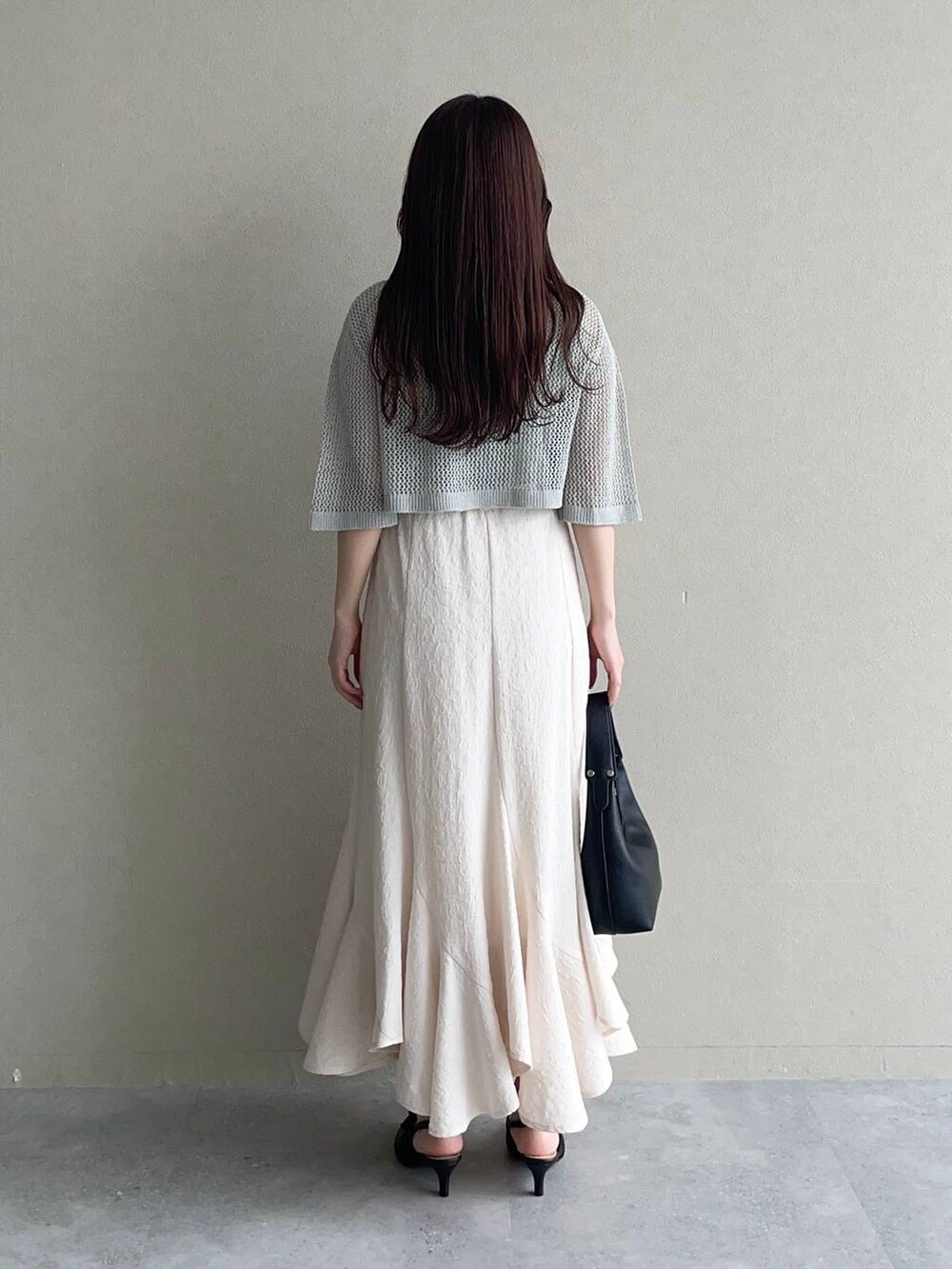 ホワイト系のスカート、グリーン系のカーディガン/ボレロ、ブラック系のショルダーバッグを着用したレディースの春コーディネートの2枚目の写真