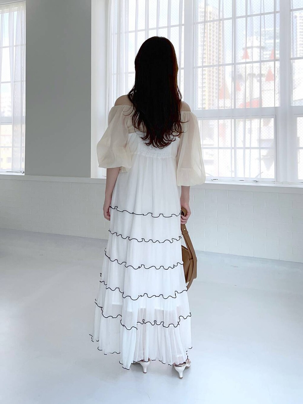 ブラウン系のショルダーバッグ、ホワイト系のサンダル、ベージュ系のTシャツ/カットソーを着用したレディースの夏コーディネートの2枚目の写真