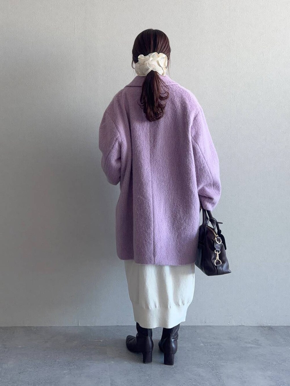 ブラウン系のボストンバッグ、パープル系のチェスターコート、ブラウン系のブーツを着用したレディースの冬コーディネートの2枚目の写真