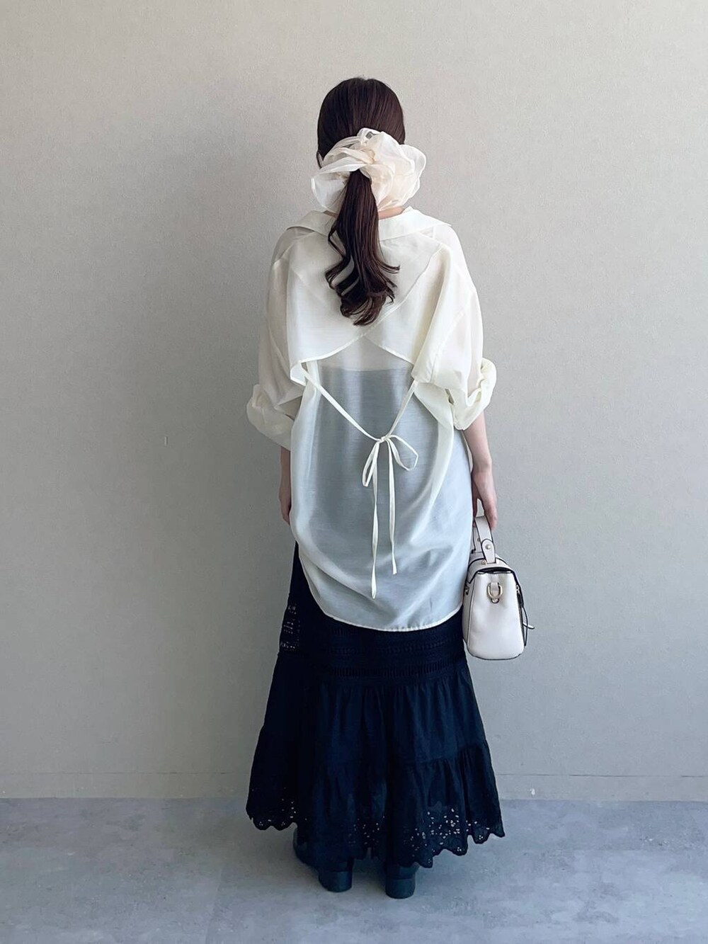 ホワイト系のショルダーバッグ、ホワイト系のシャツ/ブラウス、ブラック系のスカートを着用したレディースの夏コーディネートの2枚目の写真