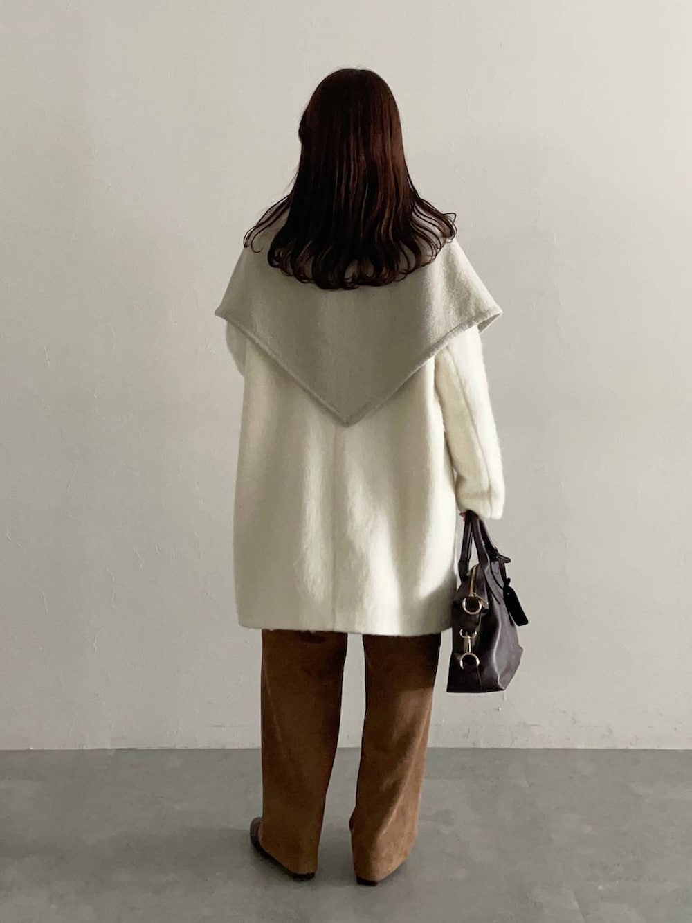 ブラウン系のボストンバッグ、ホワイト系のチェスターコート、ブラウン系のブーツを着用したレディースの秋コーディネートの2枚目の写真