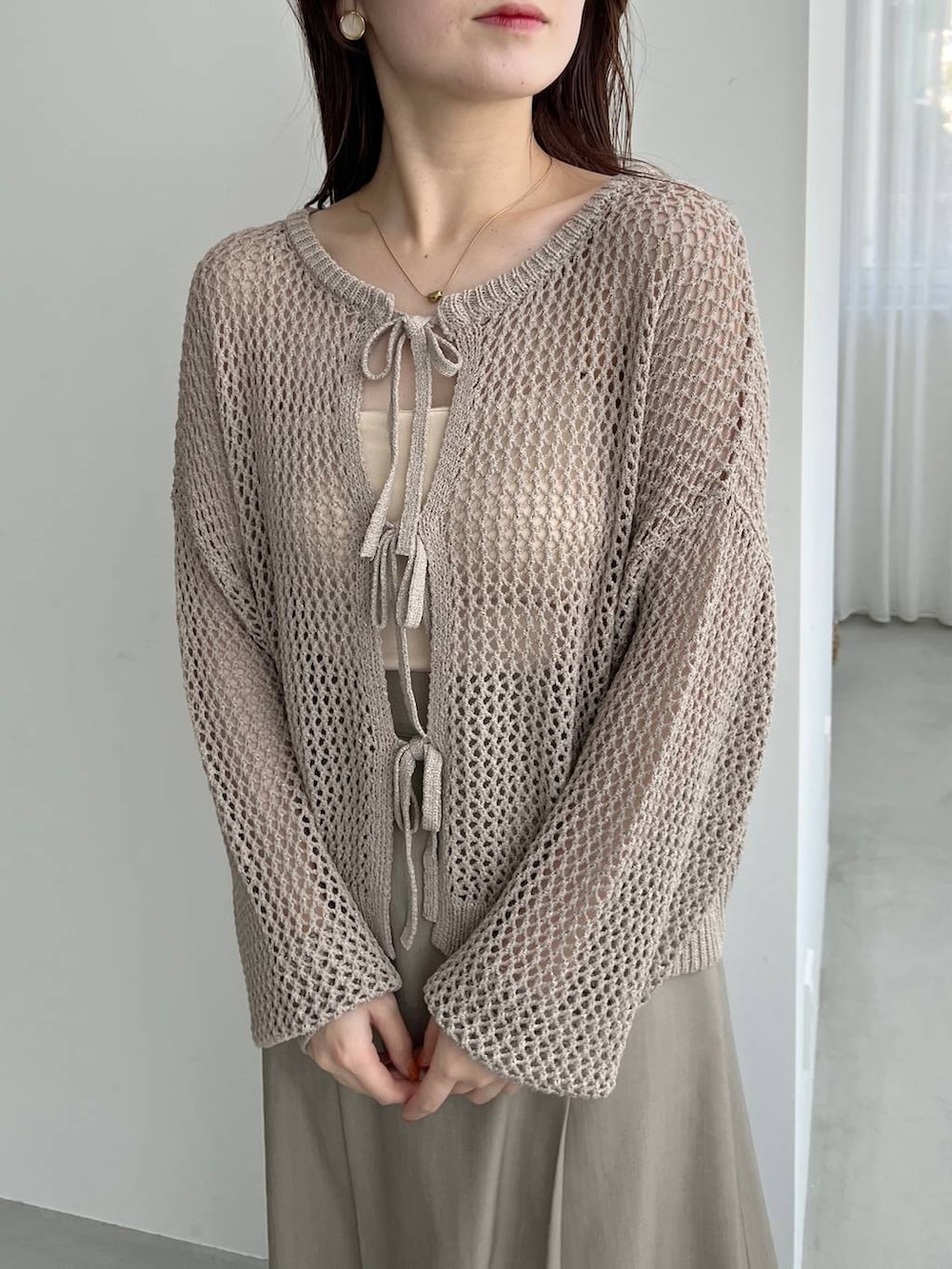 ゴールド系のパンプス、ホワイト系のショルダーバッグ、ベージュ系のニット/セーターを着用したレディースの夏コーディネートの3枚目の写真