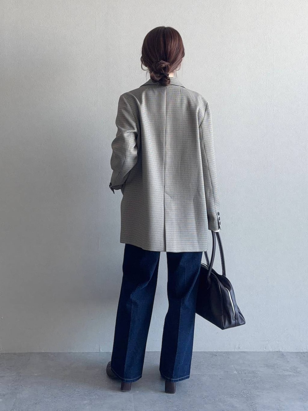 ベージュ系のテーラードジャケット、ブルー系のデニムパンツ、ブラウン系のブーツを着用したレディースの冬コーディネートの2枚目の写真