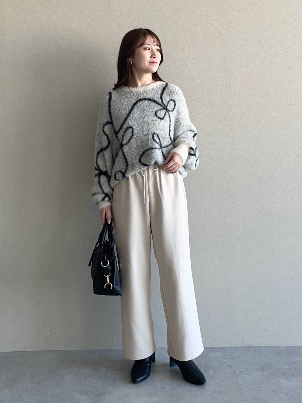 グレー系のピーコート、ブラック系のボストンバッグ、ブラック系のブーツを着用したレディースの冬コーディネートの3枚目の写真