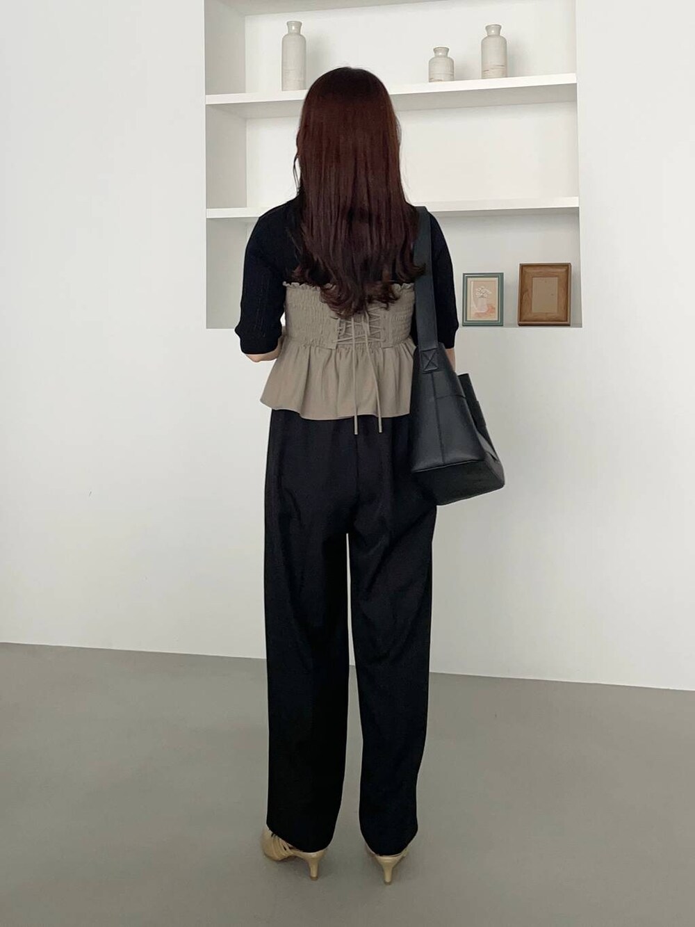 ブラック系のスラックス、ゴールド系のパンプス、グリーン系のスカートを着用したレディースの夏コーディネートの3枚目の写真