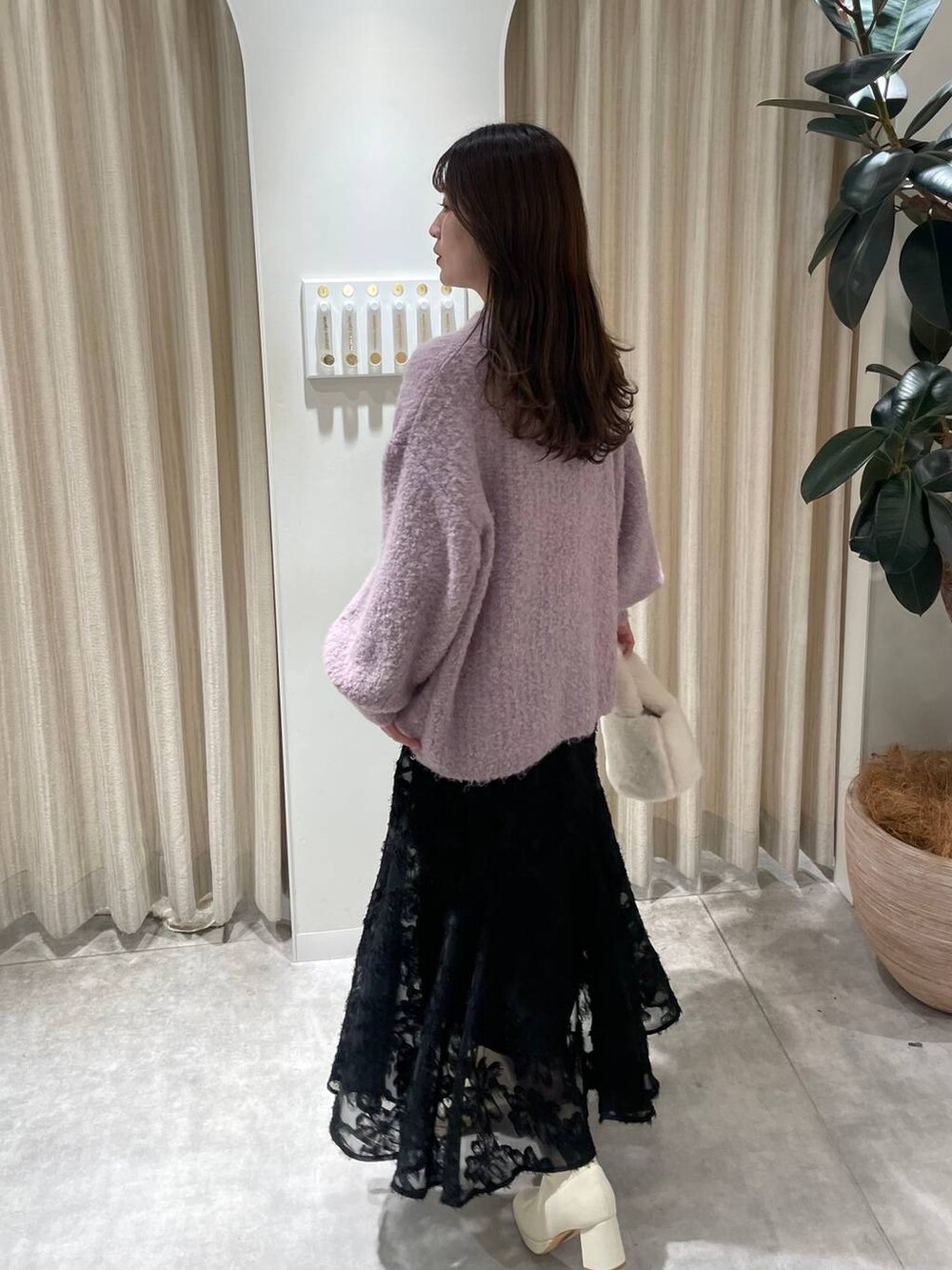 ホワイト系のブーツ、ピンク系のニット/セーター、ホワイト系のハンドバッグを着用したレディースの冬コーディネートの5枚目の写真