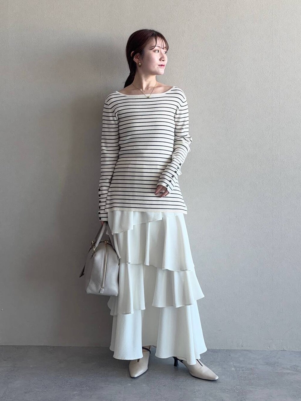 ベージュ系のハンドバッグ、ホワイト系のサンダル、ブルー系のトレンチコートを着用したレディースの冬コーディネートの3枚目の写真