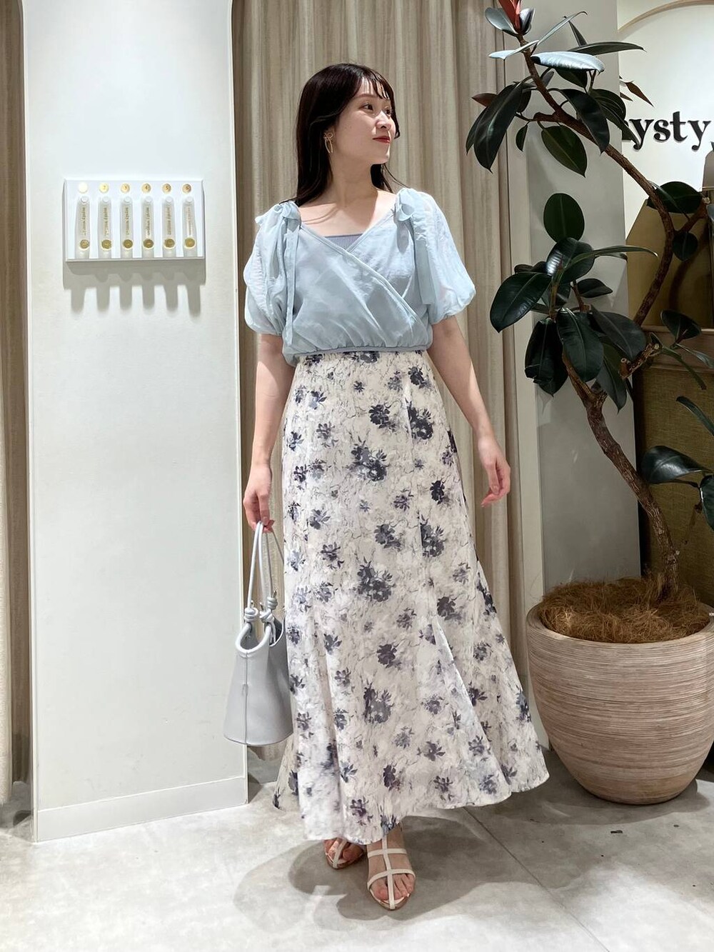 シルバー系のハンドバッグ、ホワイト系のサンダル、ホワイト系のスカートを着用したレディースの春コーディネートの2枚目の写真