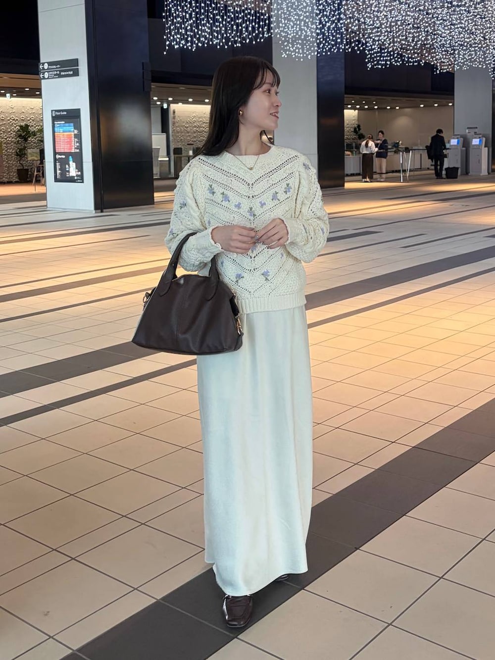 ホワイト系のスカート、ブラウン系のボストンバッグ、ホワイト系のニット/セーターを着用したレディースの冬コーディネートの2枚目の写真