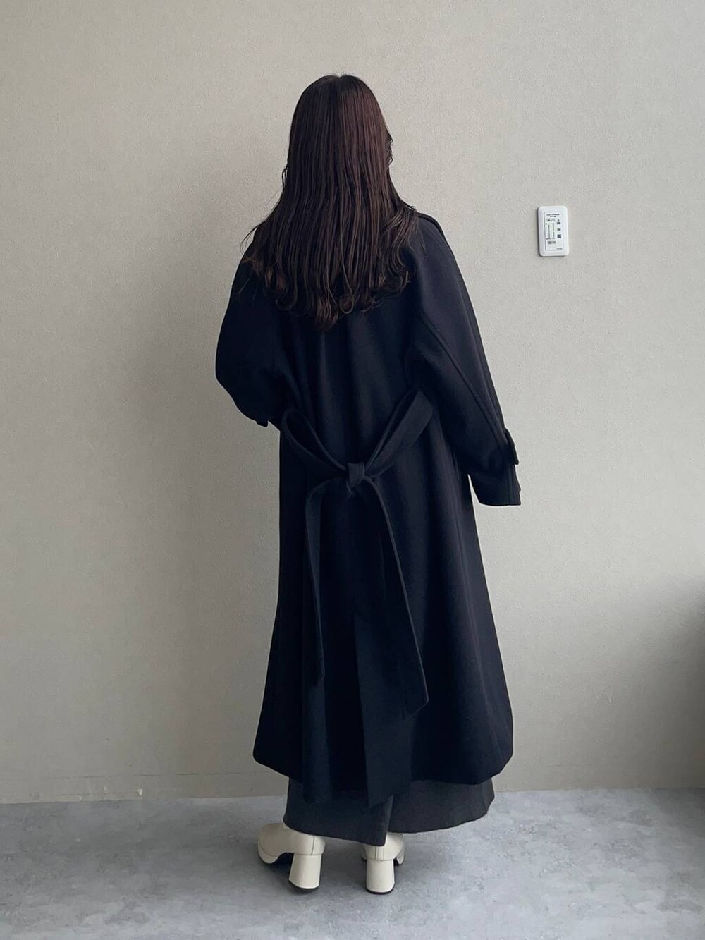 ブラック系のチェスターコート、ホワイト系のブーツ、グレー系のワンピースを着用したレディースの秋コーディネートの2枚目の写真