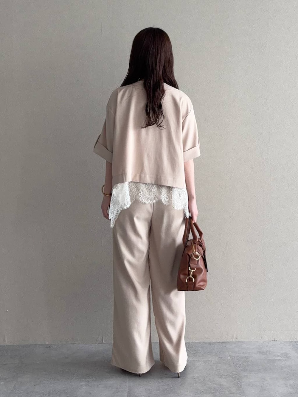 ブラウン系のボストンバッグ、ブラウン系のサンダル、ホワイト系のキャミソールを着用したレディースの春コーディネートの2枚目の写真