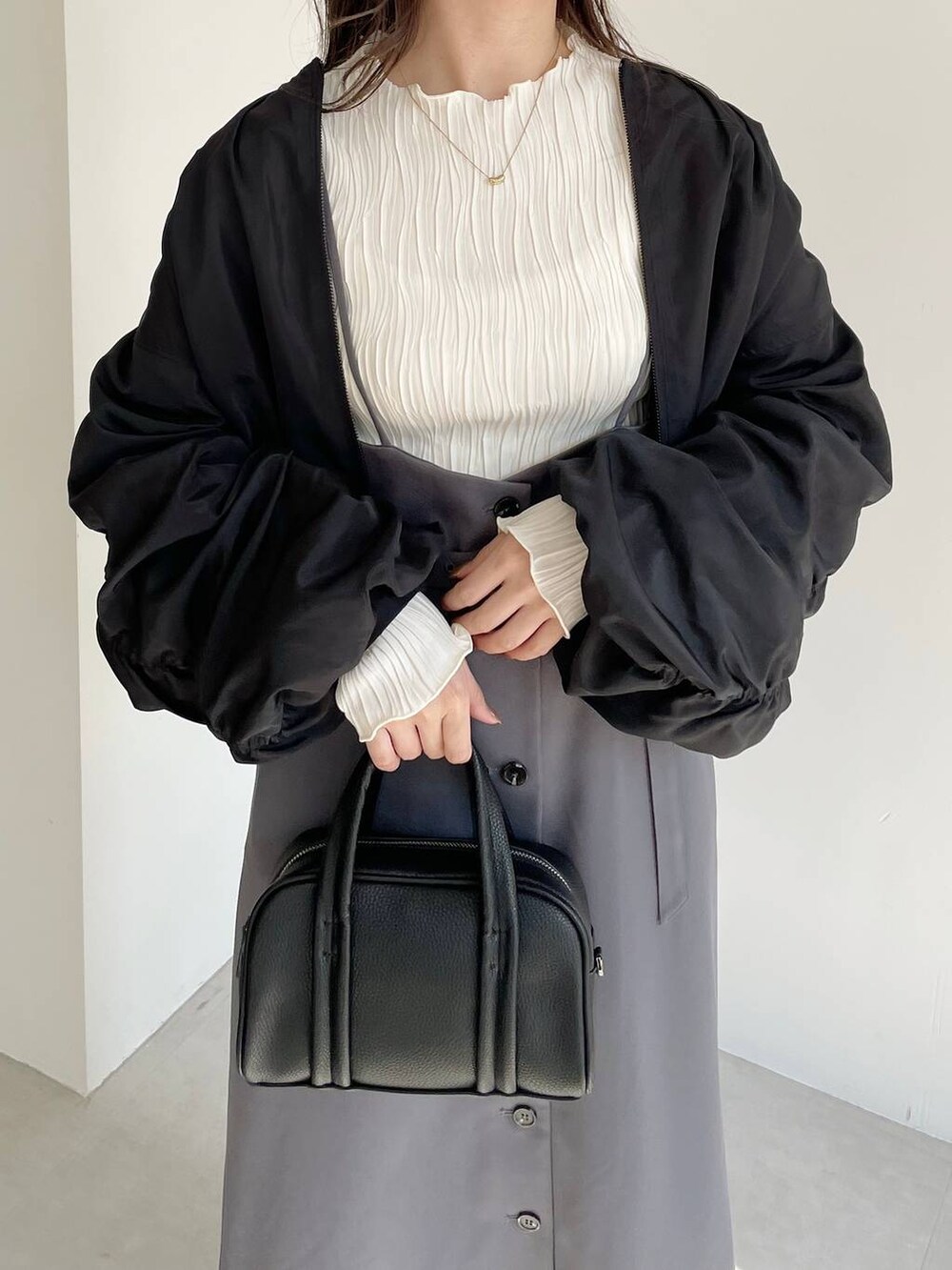 ブラック系のボストンバッグ、ブラック系のブーツ、グレー系のスカートを着用したレディースの秋コーディネートの3枚目の写真