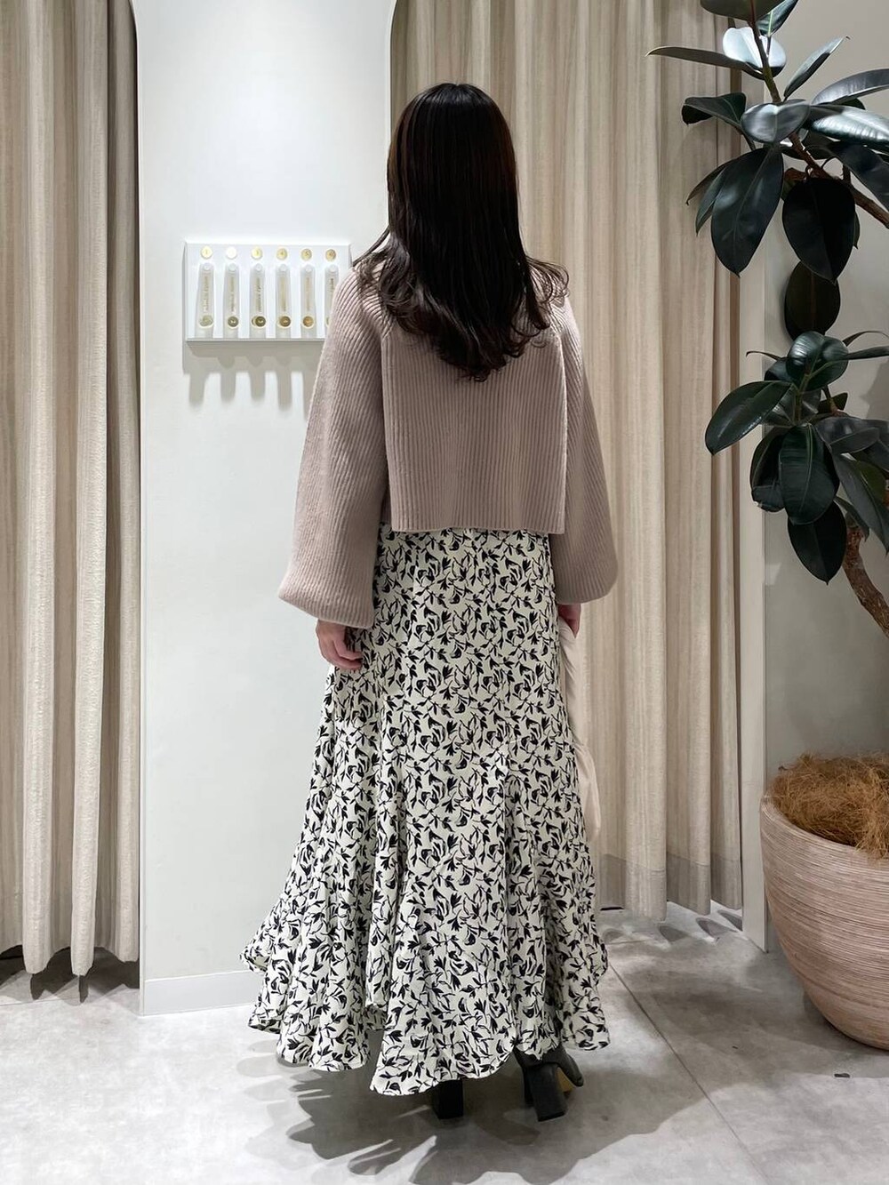 グレー系のブーツ、ホワイト系のハンドバッグ、ホワイト系のスカートを着用したレディースの秋コーディネートの2枚目の写真