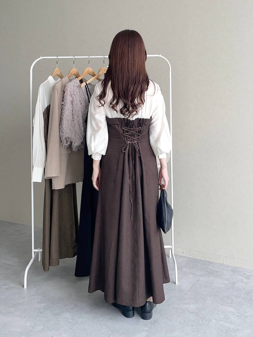 ブラック系のハンドバッグ、ブラウン系のワンピース、ブラック系のローファーを着用したレディースの秋コーディネートの2枚目の写真