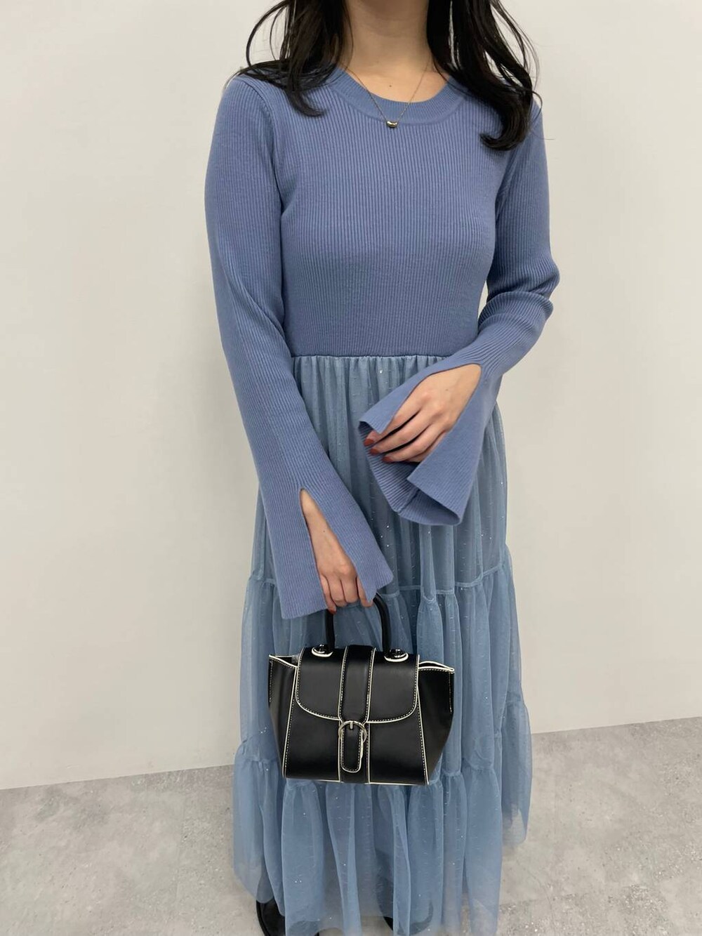 ブルー系のノーカラーコート、ブラック系のハンドバッグ、ブラック系のブーツを着用したレディースの秋コーディネートの6枚目の写真