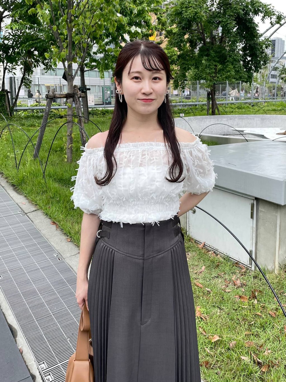 ブラウン系のショルダーバッグ、グレー系のスカート、ホワイト系のシャツ/ブラウスを着用したレディースの夏コーディネートの3枚目の写真