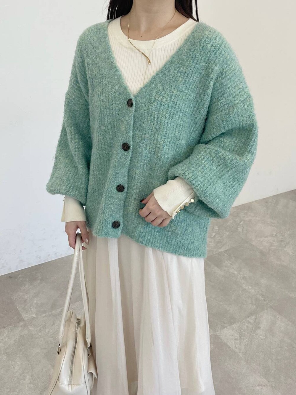 ホワイト系のブーツ、ホワイト系のニット/セーター、グリーン系のカーディガン/ボレロを着用したレディースの冬コーディネートの3枚目の写真