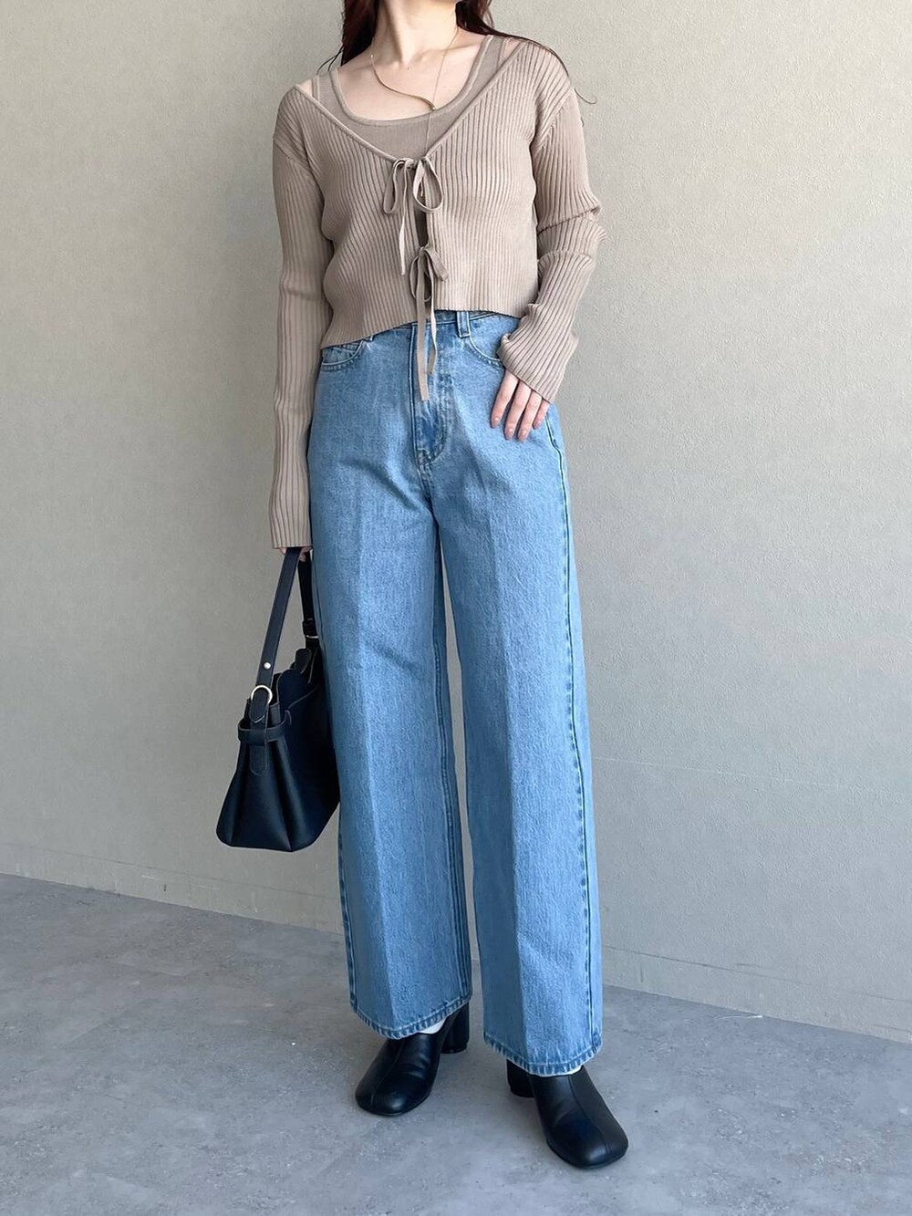 ブラック系のショルダーバッグ、ブルー系のデニムパンツ、ブラック系のパンプスを着用したレディースの冬コーディネートの4枚目の写真