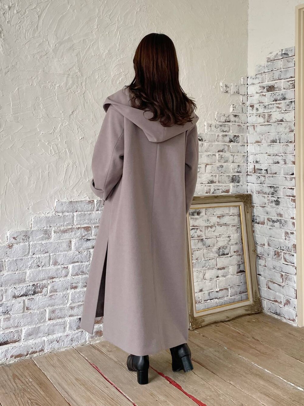 グレー系のノーカラーコート、ブラック系のブーツ、ブラック系のニット/セーターを着用したレディースの秋コーディネートの2枚目の写真