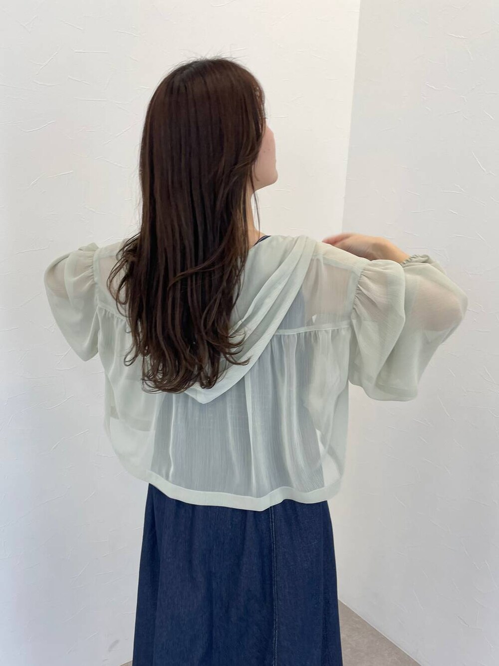 ホワイト系のハンドバッグ、グリーン系のパーカー、ブルー系のジャンパースカートを着用したレディースの春コーディネートの4枚目の写真