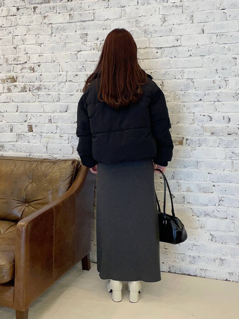 ブラック系のブルゾン、ホワイト系のブーツ、ブラック系のハンドバッグを着用したレディースの秋コーディネートの2枚目の写真