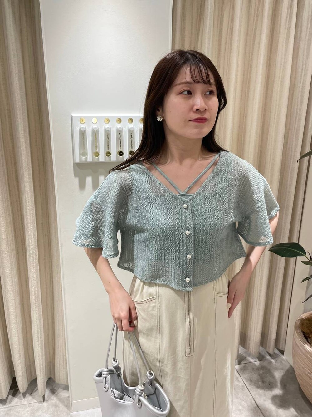 シルバー系のバレエシューズ、グリーン系のカーディガン/ボレロ、ホワイト系のスカートを着用したレディースの春コーディネートの4枚目の写真