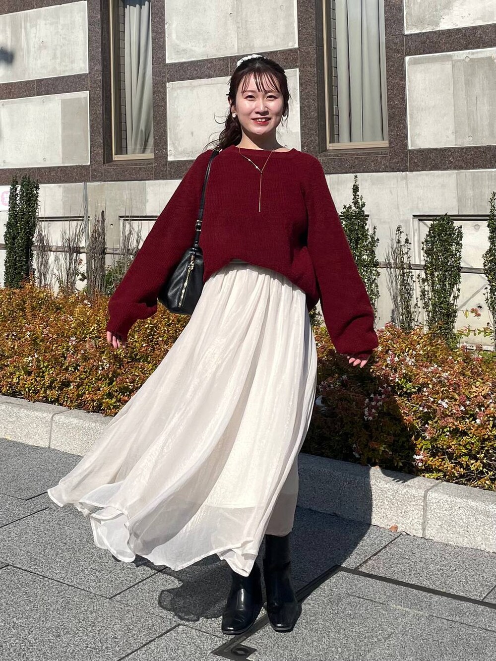 レッド系のニット/セーター、ホワイト系のブルゾン、ホワイト系のスカートを着用したレディースの秋コーディネートの5枚目の写真