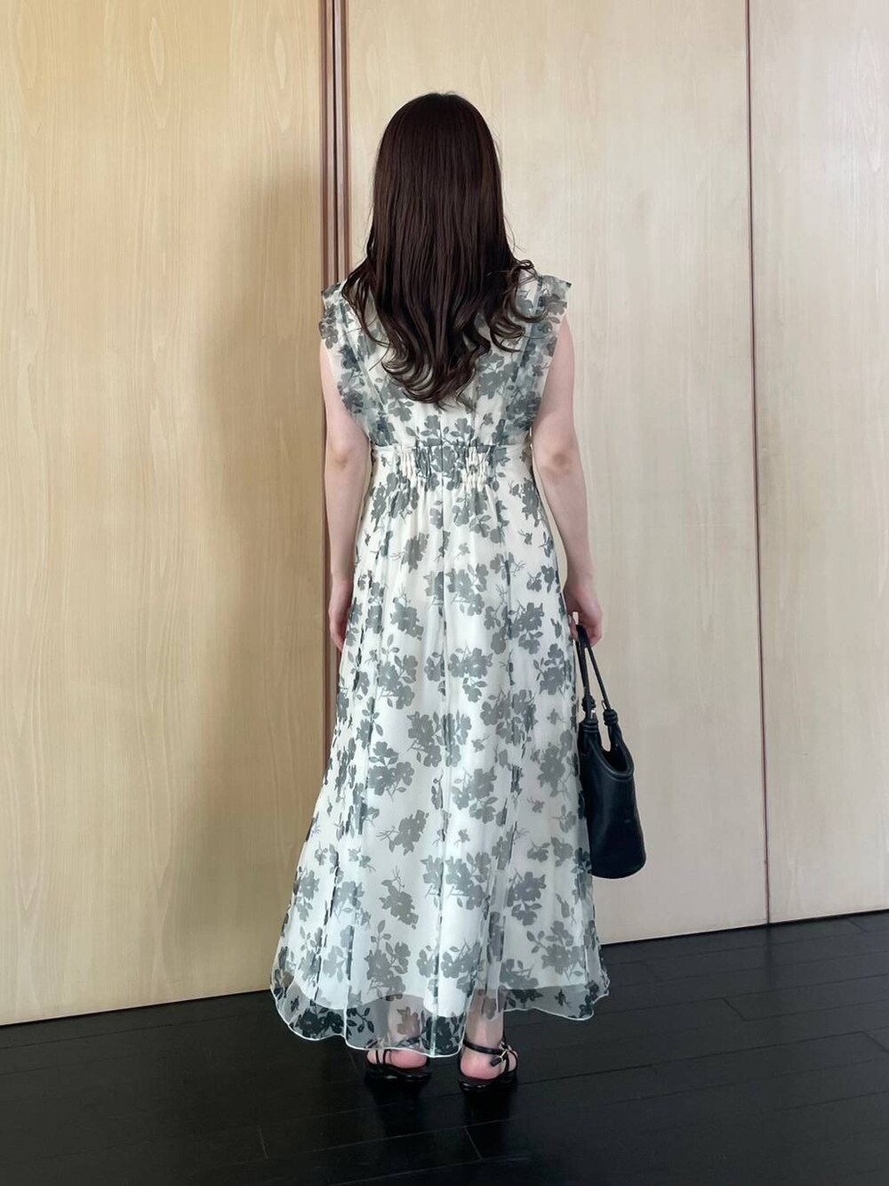 ブラック系のハンドバッグ、ブラック系のサンダル、ホワイト系のワンピースを着用したレディースの春コーディネートの2枚目の写真