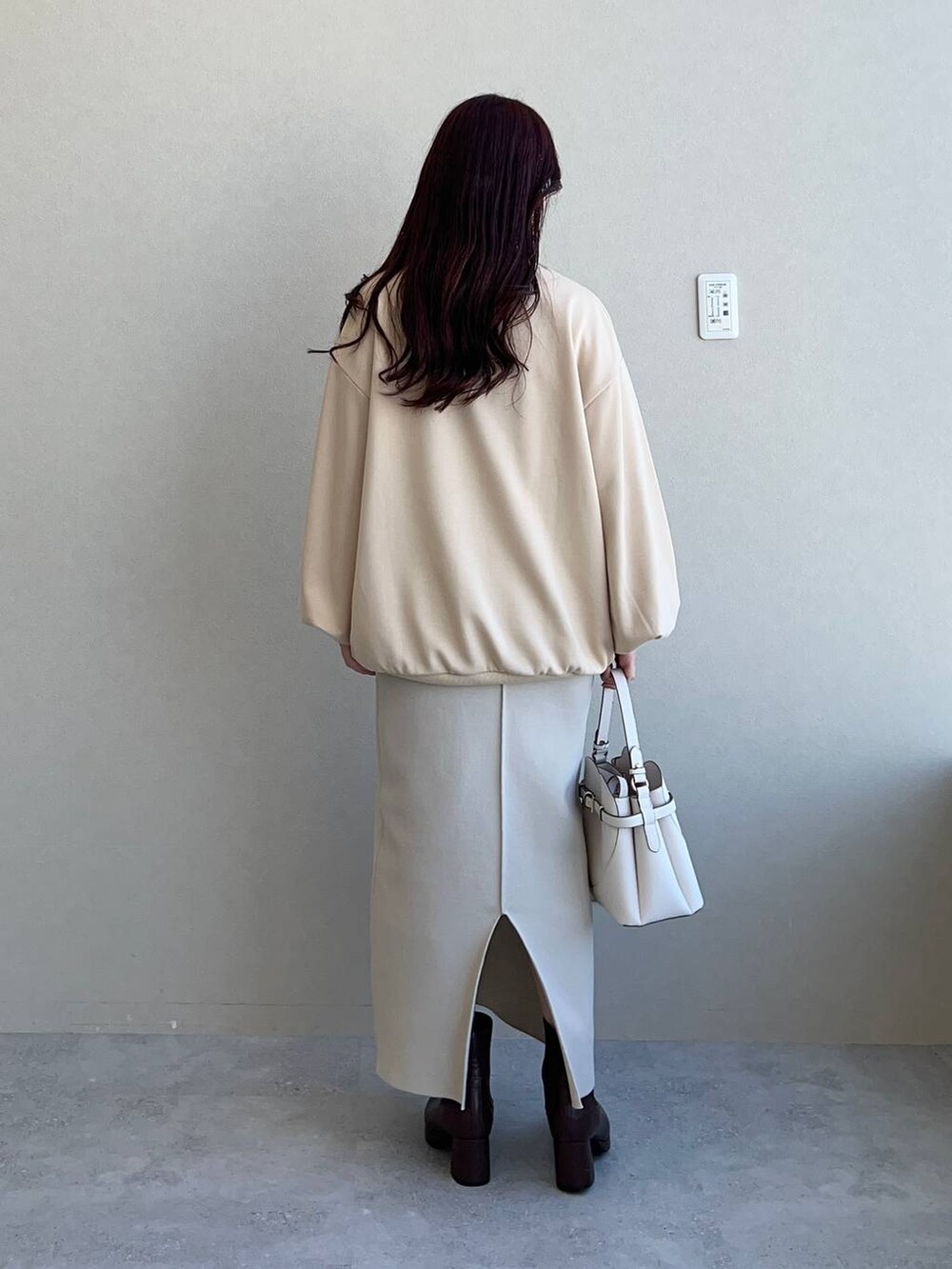 ホワイト系のショルダーバッグ、ブラウン系のブーツ、ベージュ系のスウェットを着用したレディースの冬コーディネートの2枚目の写真