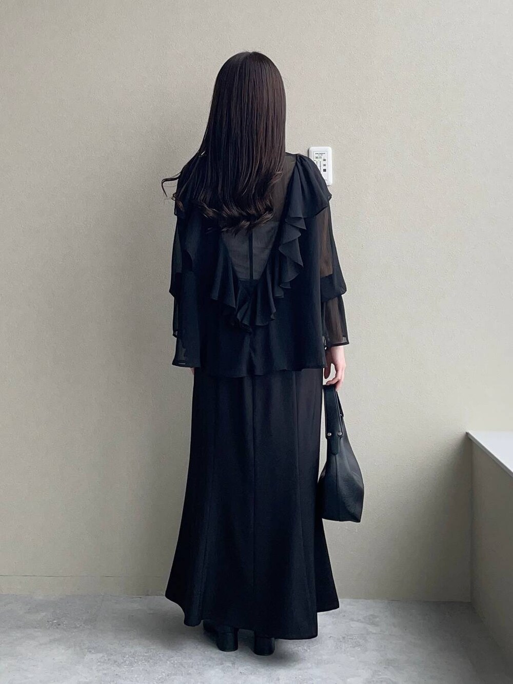 ブラック系のスカート、ブラック系のローファー、ブラック系のショルダーバッグを着用したレディースの春コーディネートの2枚目の写真