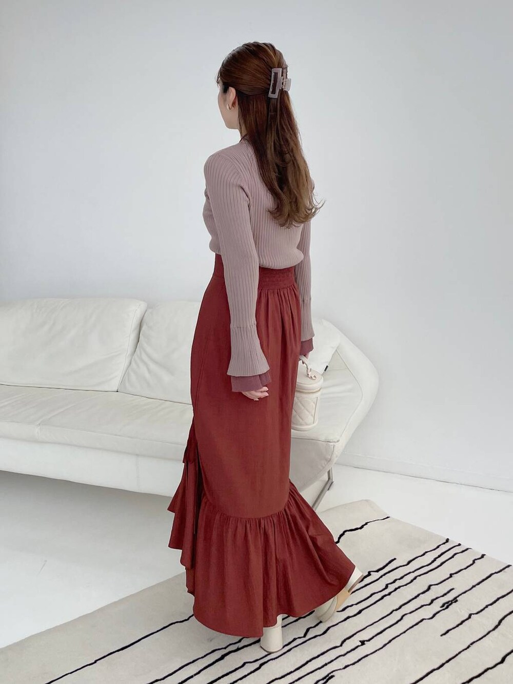 ホワイト系のブーツ、ブラウン系のニット/セーター、ホワイト系のショルダーバッグを着用したレディースの秋コーディネートの2枚目の写真