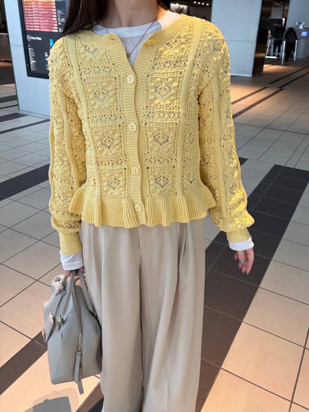 ホワイト系のTシャツ/カットソー、ベージュ系のハンドバッグ、イエロー系のカーディガン/ボレロを着用したレディースの冬コーディネートの3枚目の写真