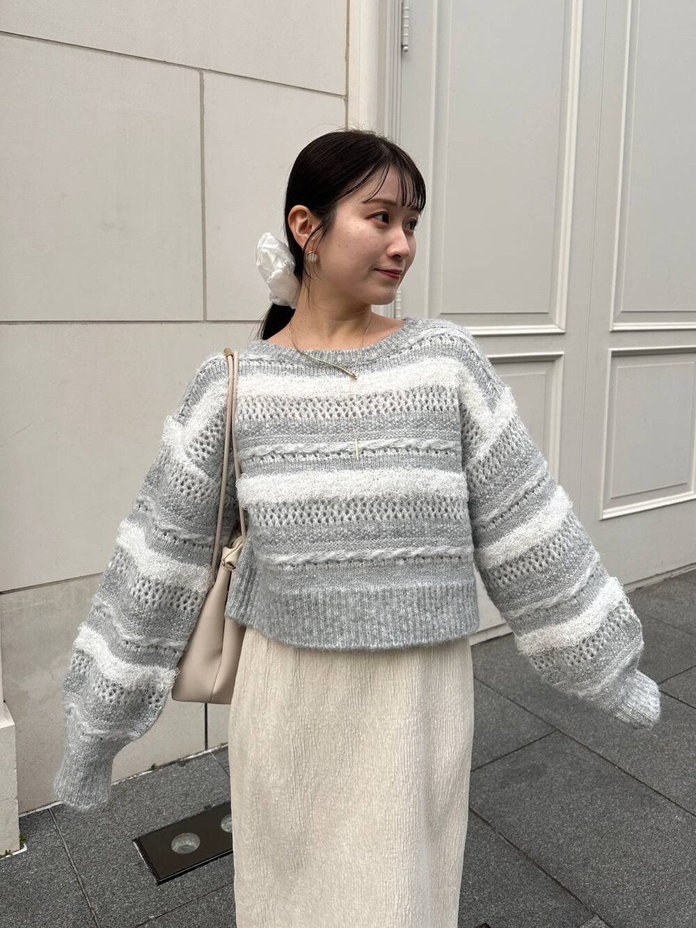 ホワイト系のスカート、グレー系のニット/セーターを着用したレディースの冬コーディネートの3枚目の写真