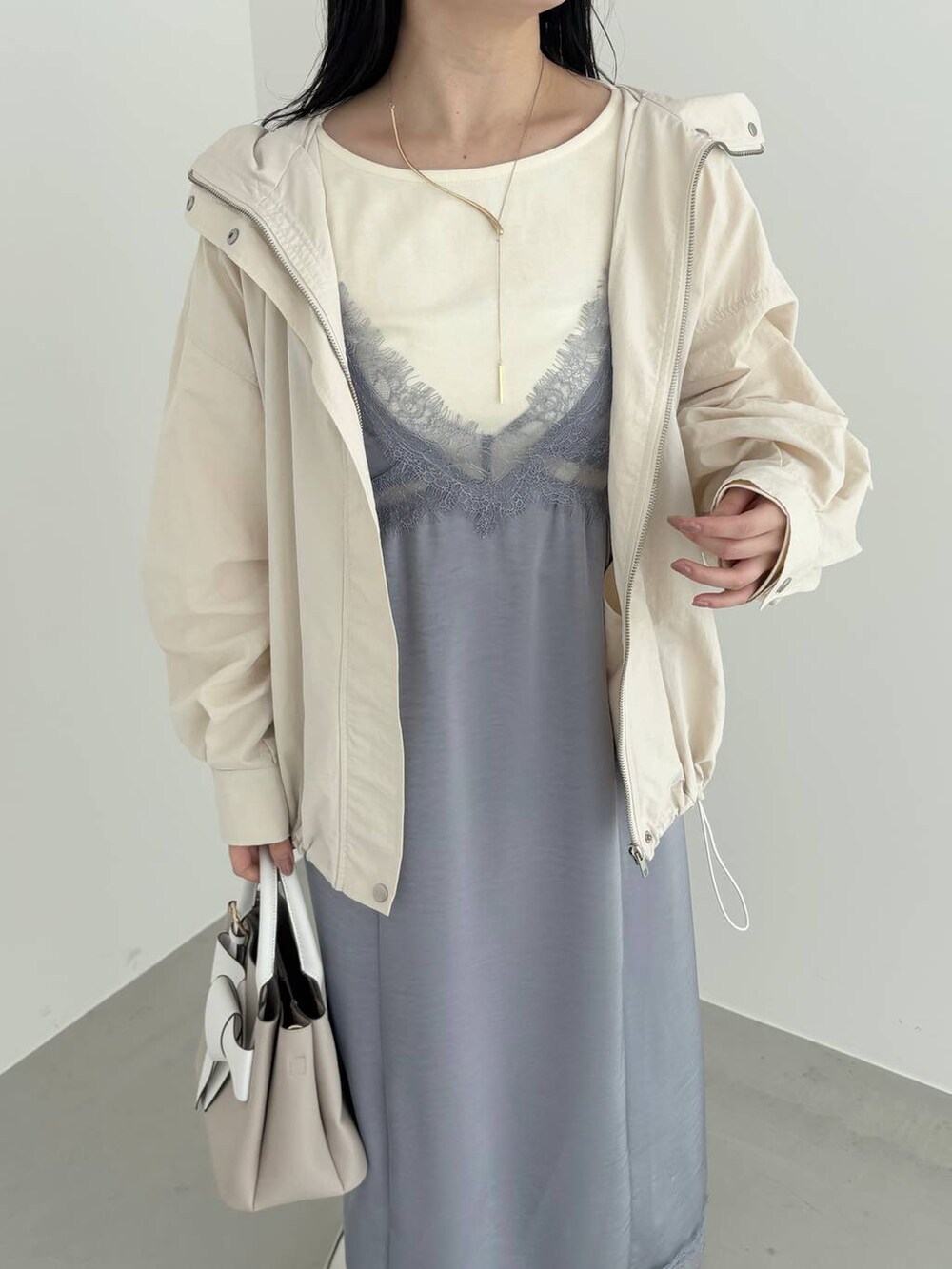 ベージュ系のショルダーバッグ、ホワイト系のマウンテンパーカー、シルバー系のバレエシューズを着用したレディースの春コーディネートの3枚目の写真