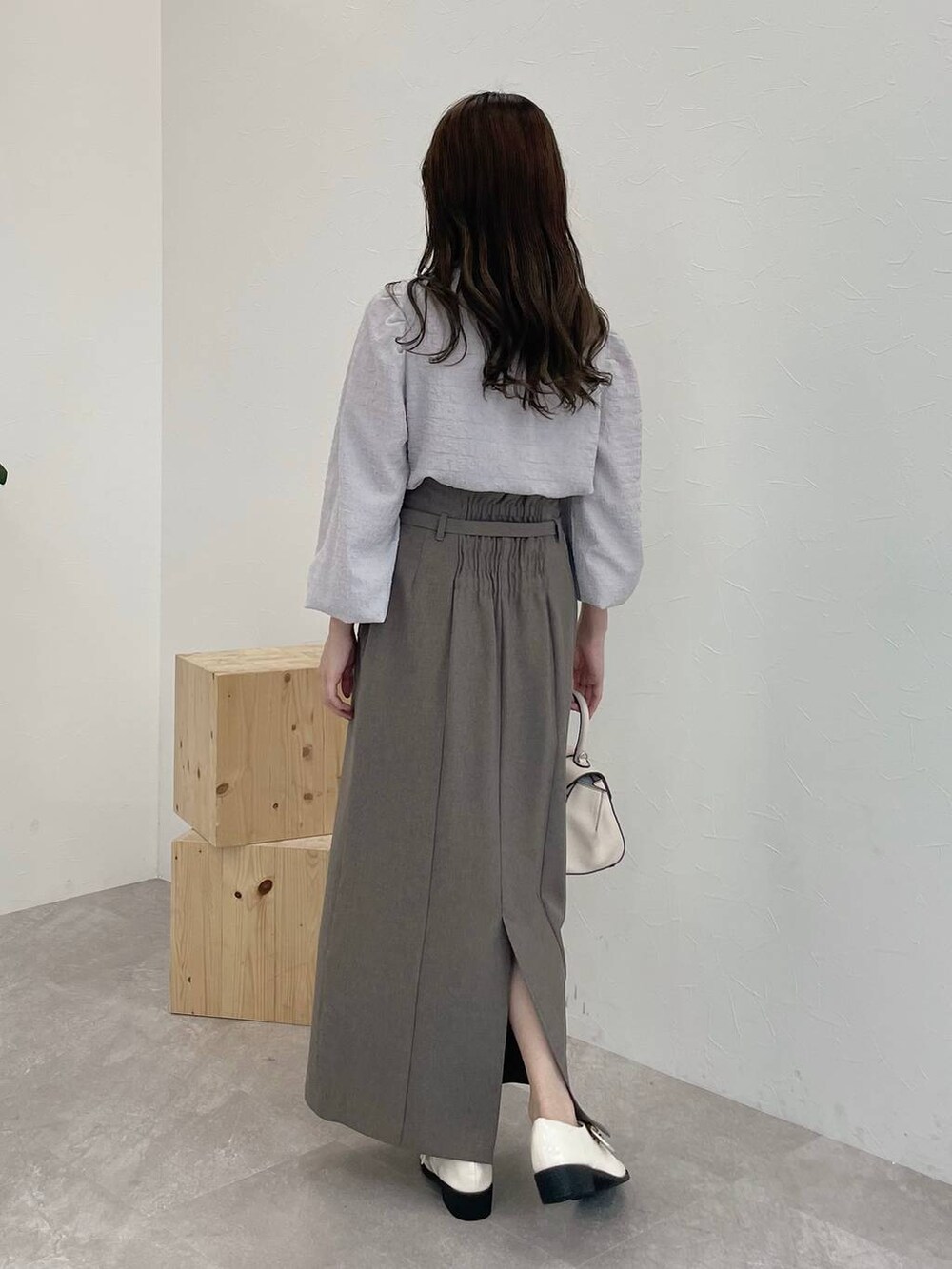 ブラウン系のスカート、ホワイト系のその他シューズ、ホワイト系のハンドバッグを着用したレディースの秋コーディネートの2枚目の写真