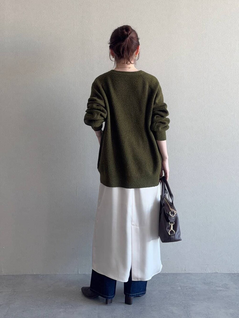 ブラウン系のボストンバッグ、ブルー系のデニムパンツ、グリーン系のニット/セーターを着用したレディースの冬コーディネートの2枚目の写真