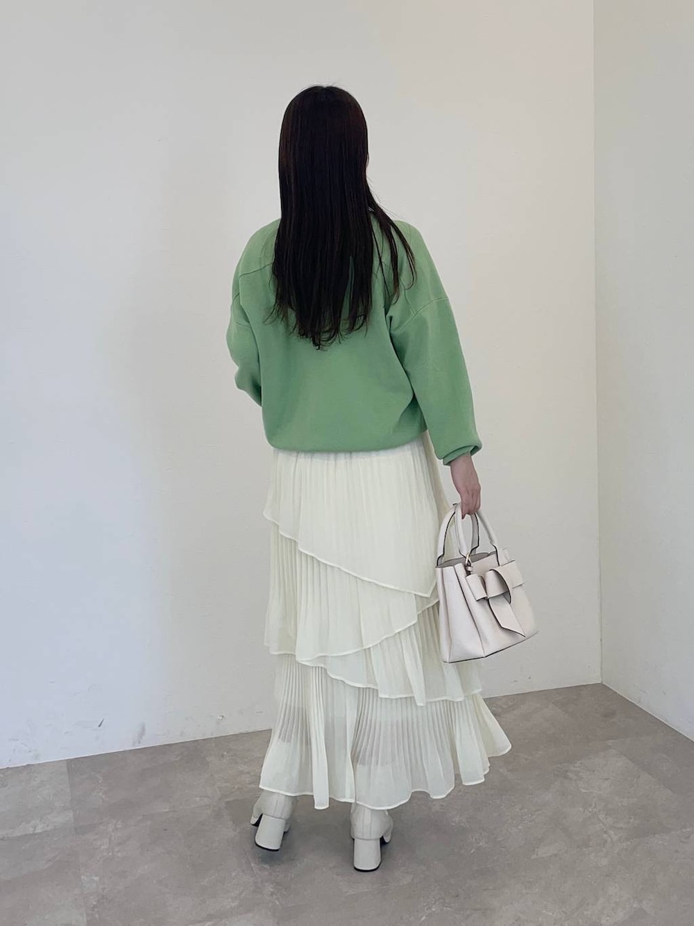 ホワイト系のブーツ、グリーン系のニット/セーター、ホワイト系のショルダーバッグを着用したレディースの冬コーディネートの2枚目の写真