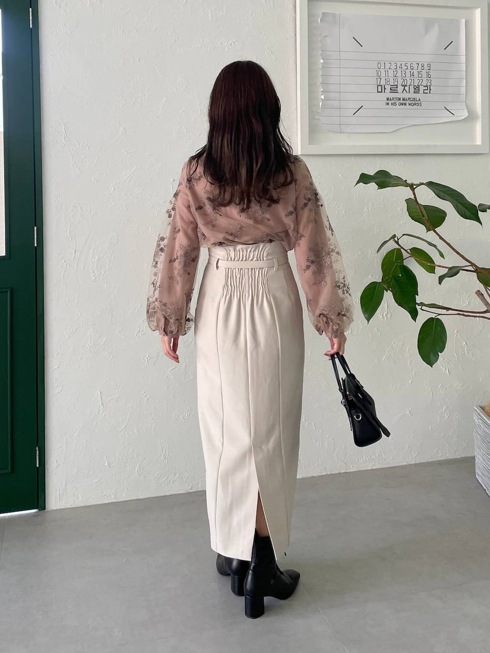 ブラック系のボストンバッグ、ホワイト系のスカート、ブラック系のブーツを着用したレディースの夏コーディネートの2枚目の写真