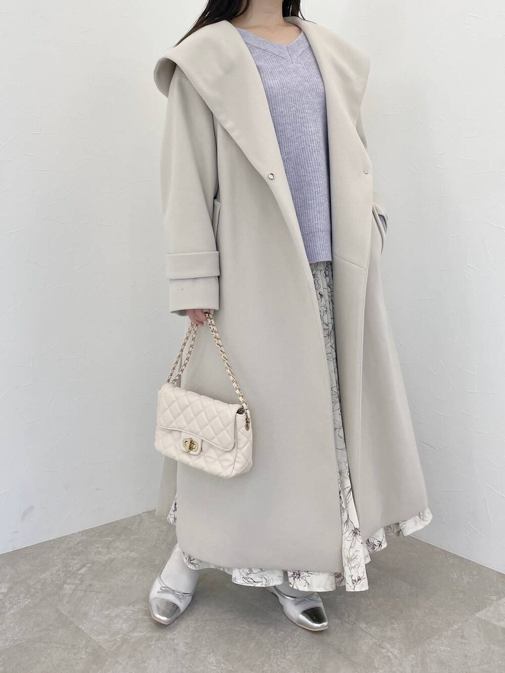 パープル系のニット/セーター、ホワイト系のショルダーバッグ、ホワイト系のノーカラーコートを着用したレディースの冬コーディネートの3枚目の写真