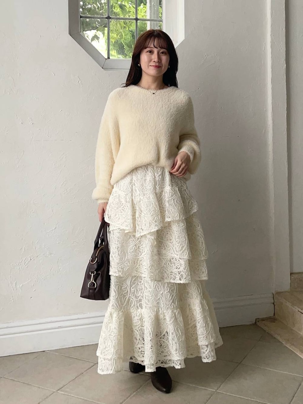 ブラウン系のボストンバッグ、ブラウン系のマウンテンパーカー、ホワイト系のスカートを着用したレディースの秋コーディネートの3枚目の写真