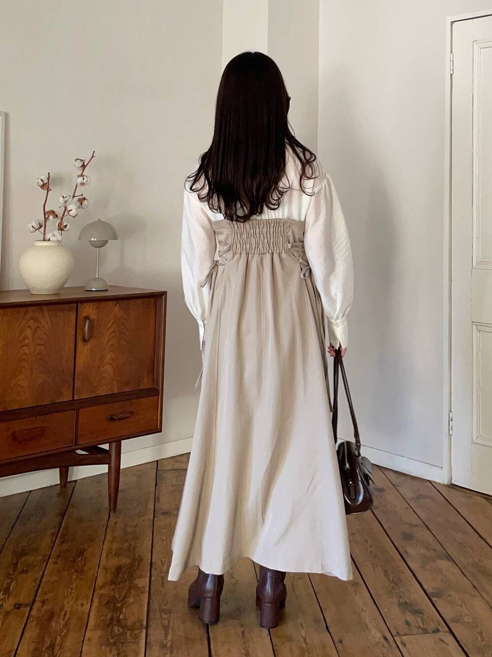 ブラウン系のブーツ、ブラウン系のハンドバッグ、ベージュ系のワンピースを着用したレディースの冬コーディネートの2枚目の写真